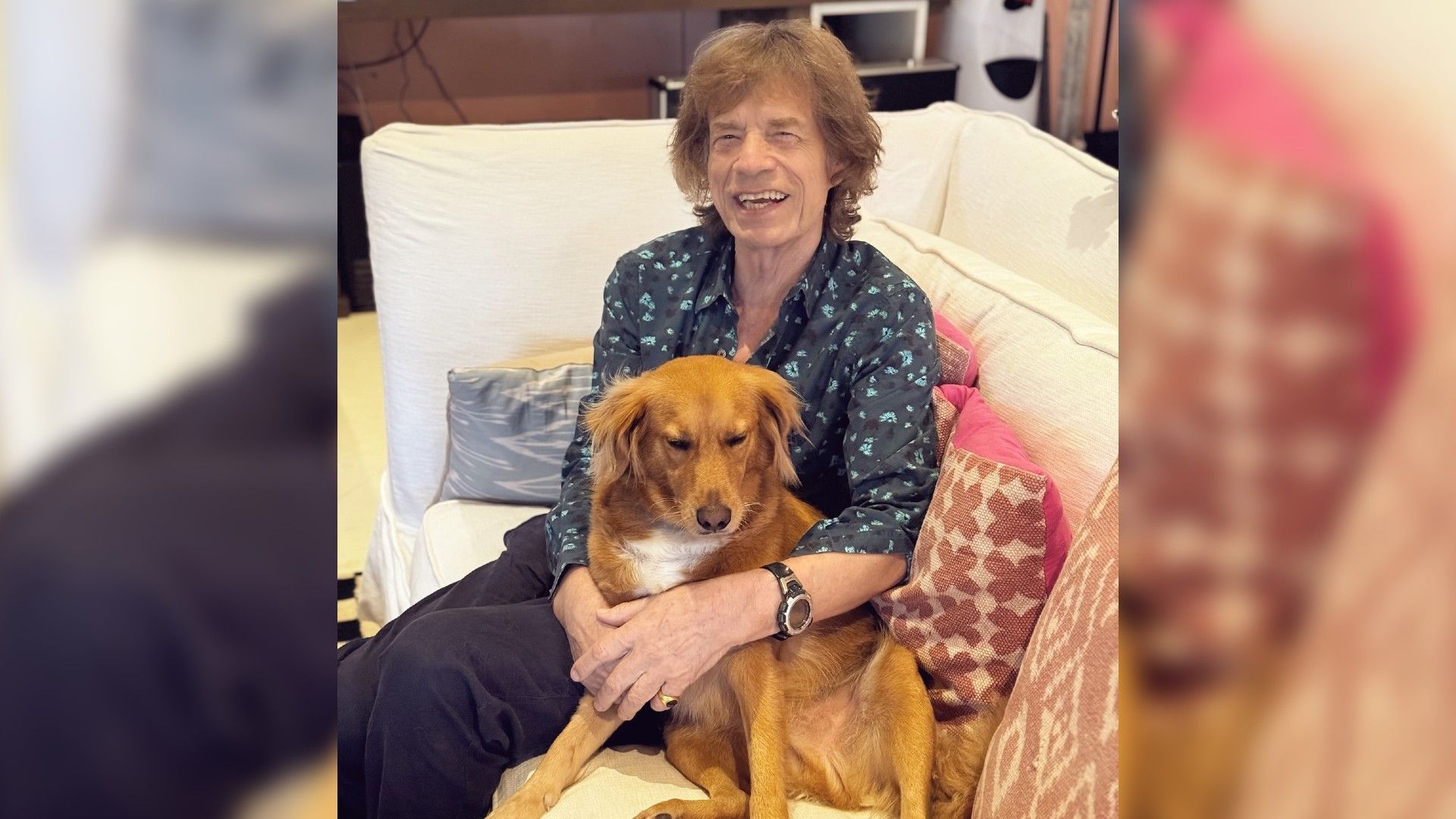 Un hombre mayor con el cabello largo está sentado en el sofá abrazando a un perro