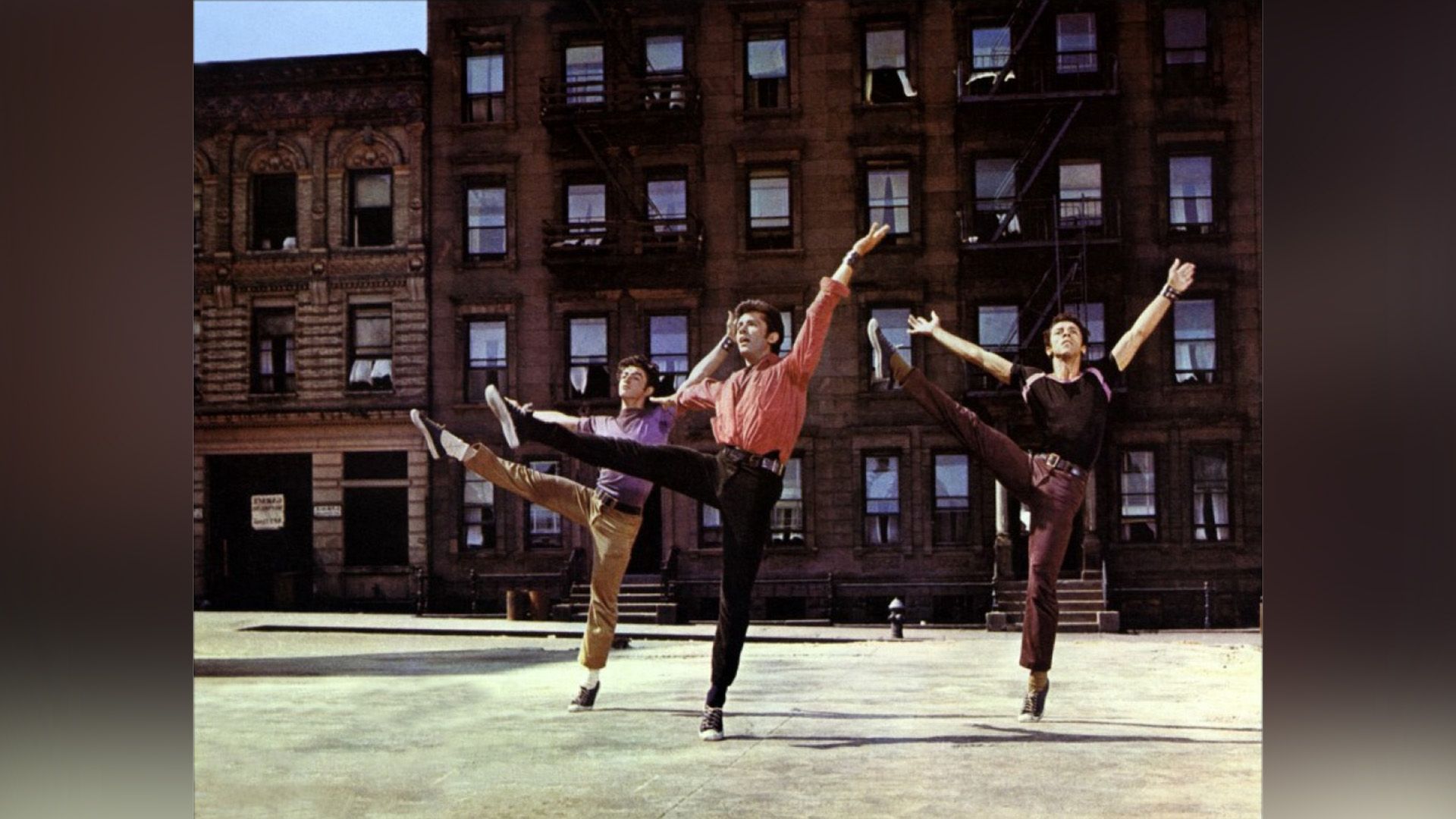 El patio frente al edificio de apartamentos, tres jóvenes en jeans y camisetas de diferentes colores están bailando