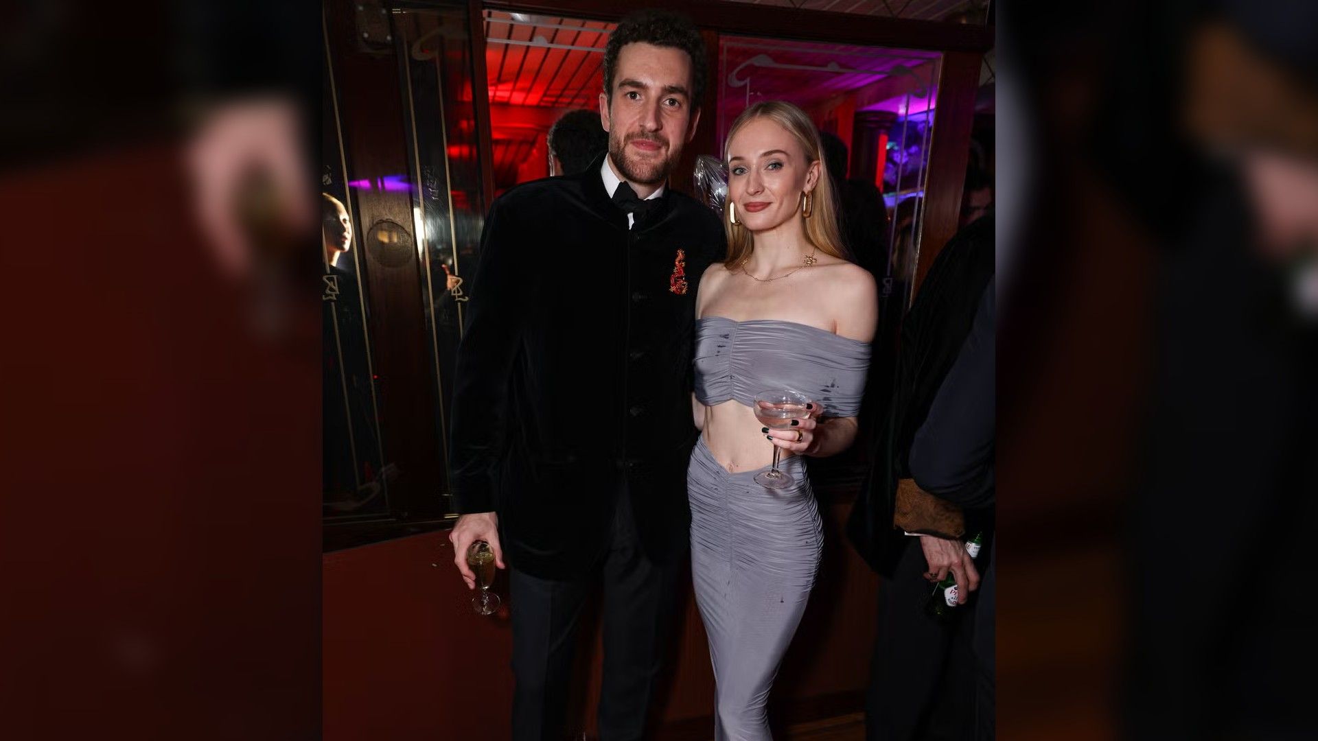 La actriz Sophie Turner en un vestido de noche azul pálido y Peregrine Pearson en un traje negro posan juntos