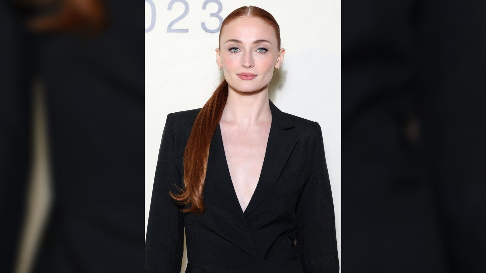 Actriz Sophie Turner fotografiada de la cintura para arriba. Cabello en una coleta y un blazer