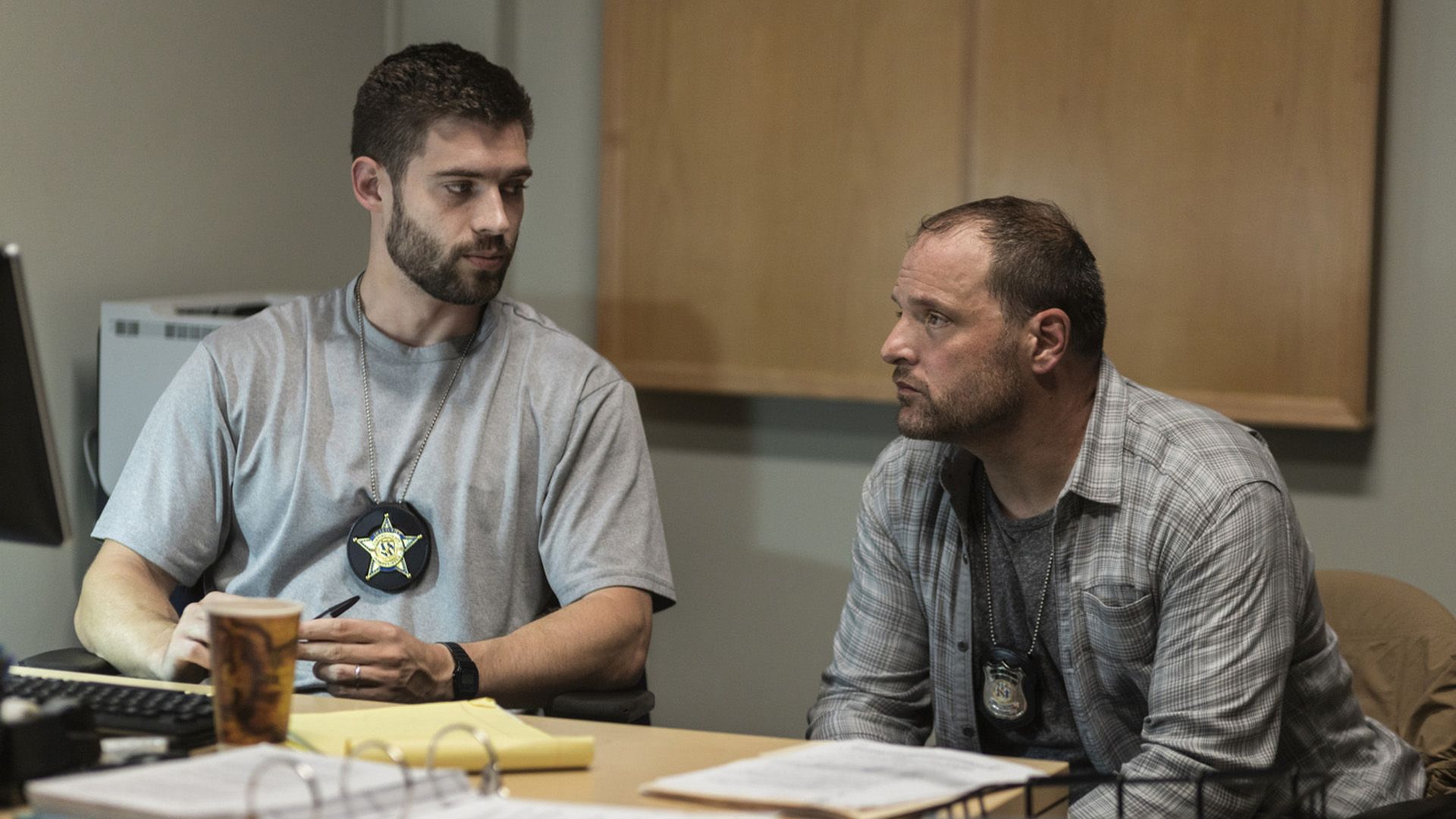 Dos policías de civil están sentados en una mesa y hablando