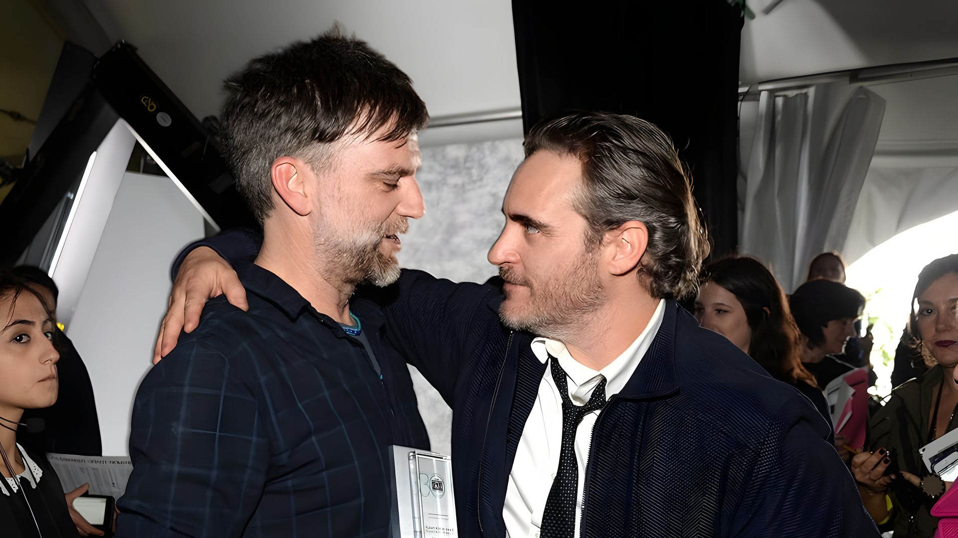 Joaquin Phoenix abraza a Paul Thomas Anderson con una mano