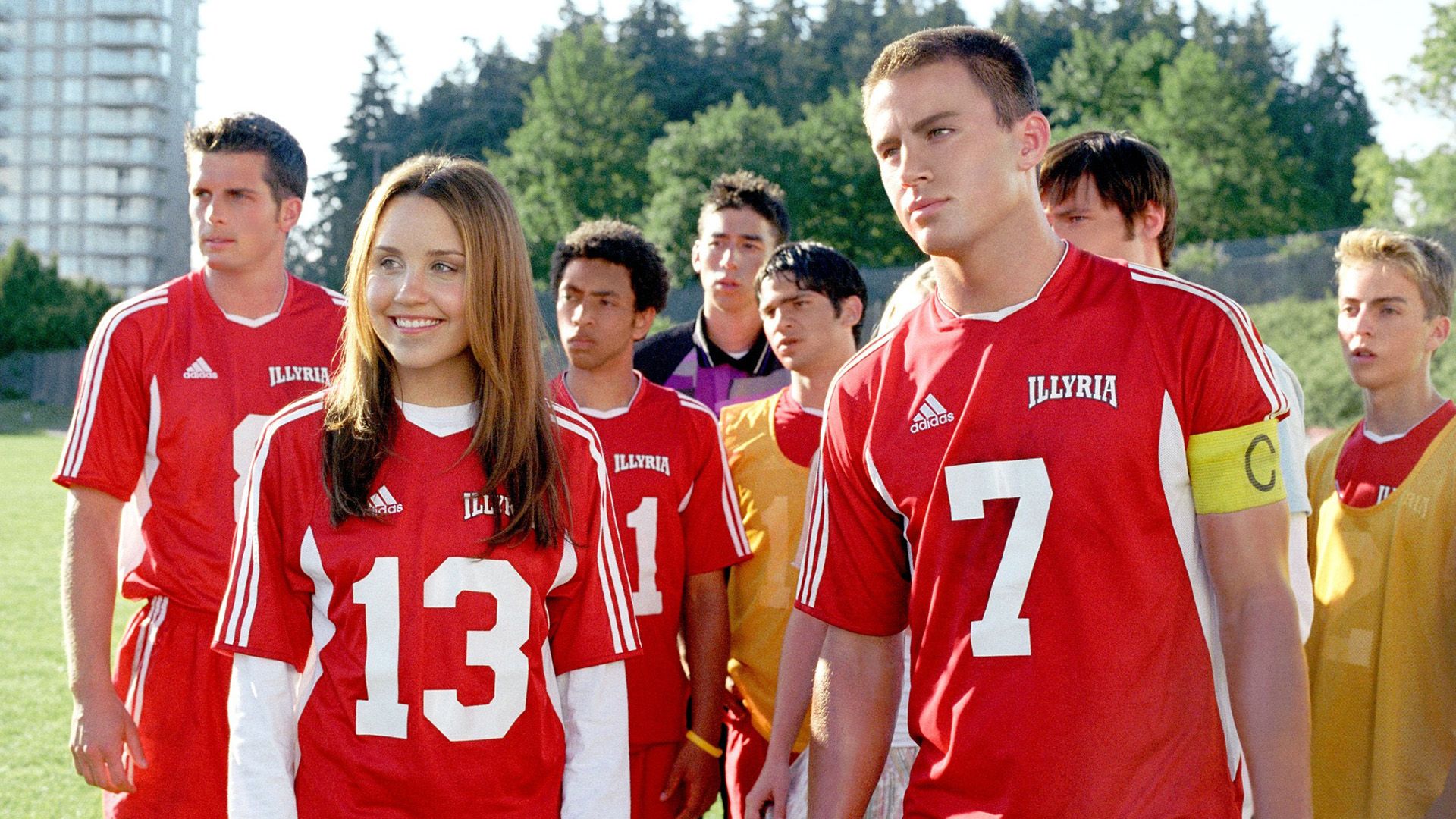 Amanda Bynes y Channing Tatum con camisetas deportivas rojas rodeados de otros jóvenes