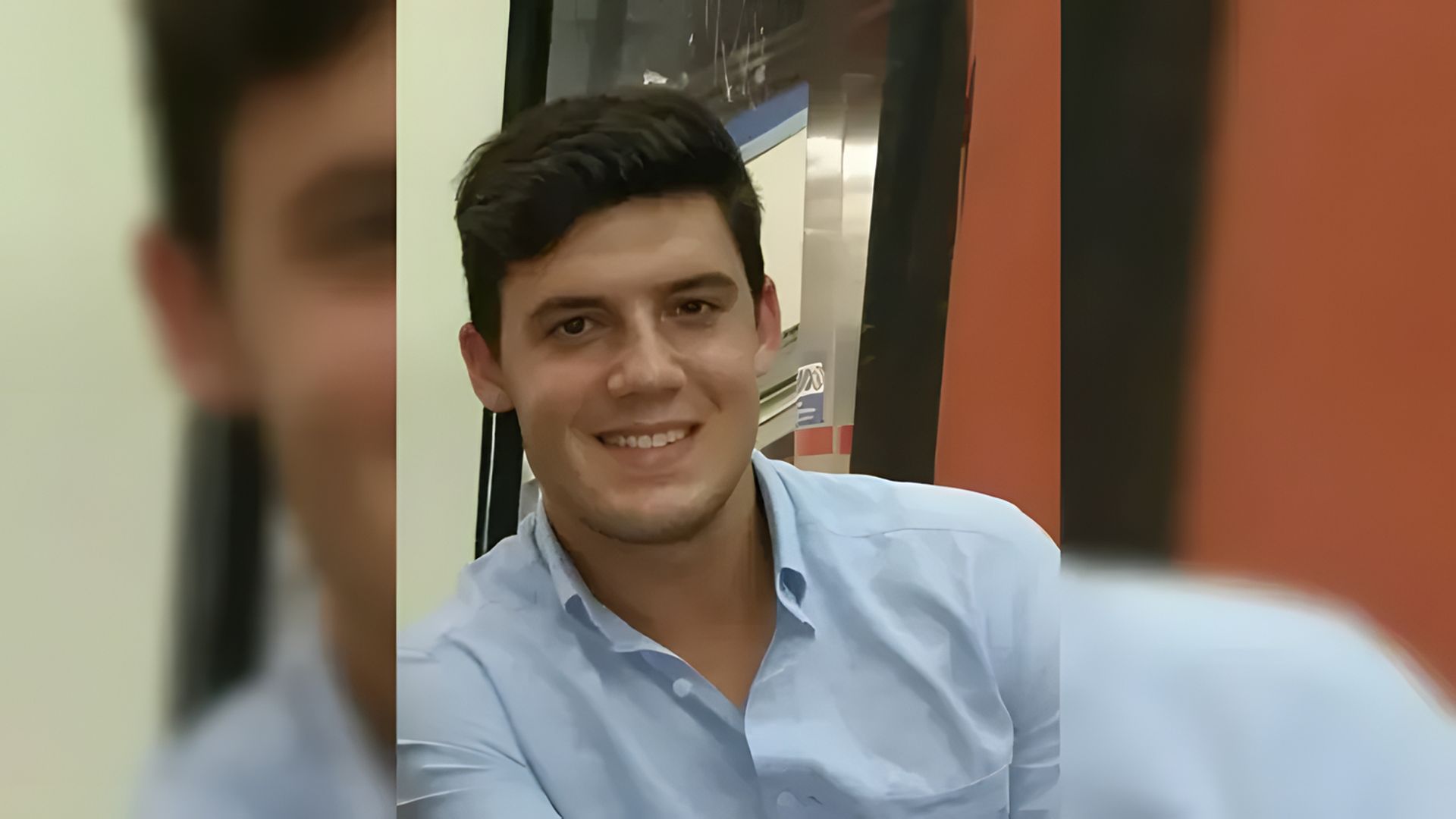 Un joven sonríe a la cámara, el fondo está desenfocado