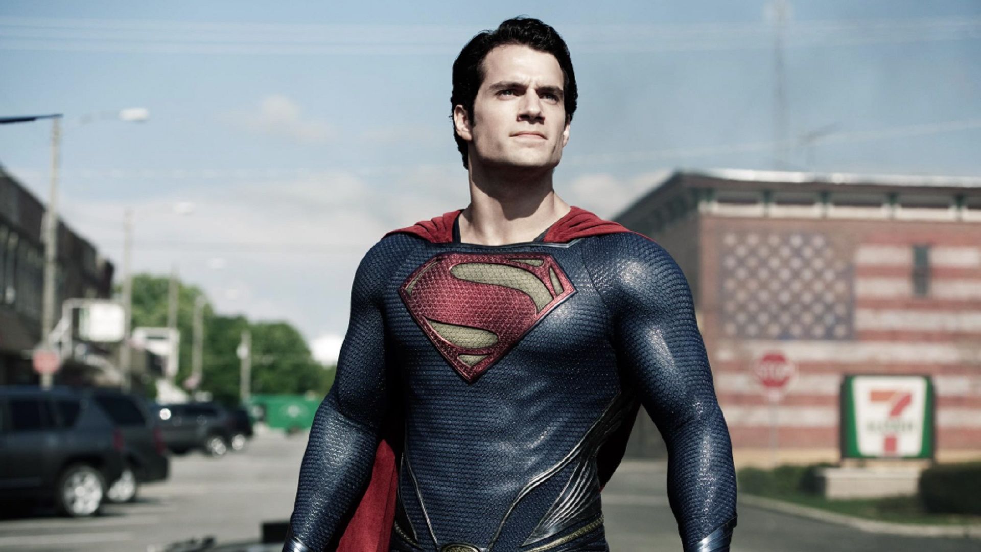 Henry Cavill en un traje de Superman mira hacia arriba mientras está de pie en la calle