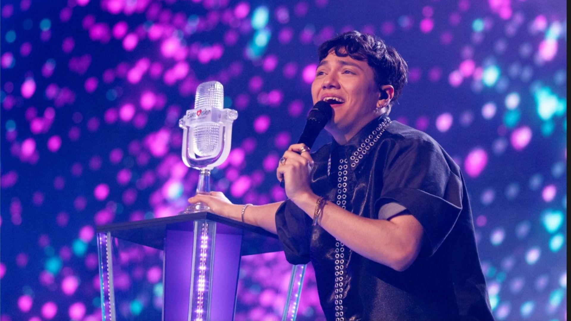 Cantante JJ en el escenario junto al pedestal con la estatuilla del concurso Eurovision 2025 y sonríe