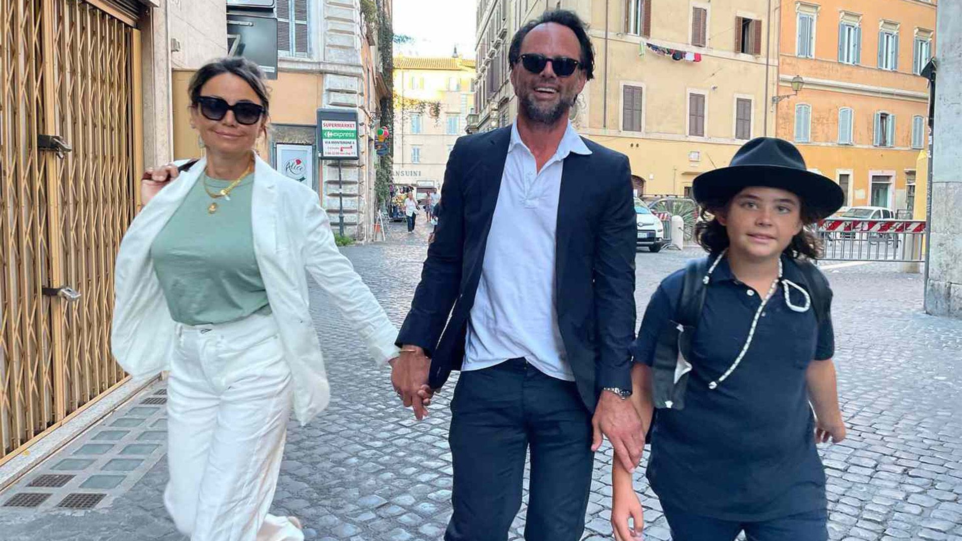 Walton Goggins, su esposa Nadia Conners y su hijo Augustus caminan por la calle sonriendo