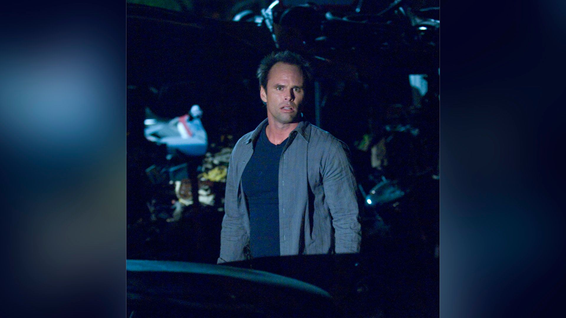 Walton Goggins stands in the dark with a frightened face