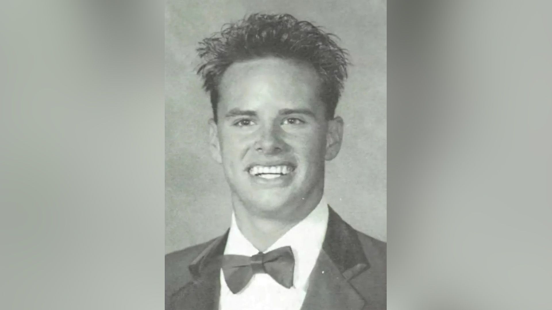 El joven Walton Goggins, vestido con una pajarita, sonríe ampliamente en una foto del álbum escolar