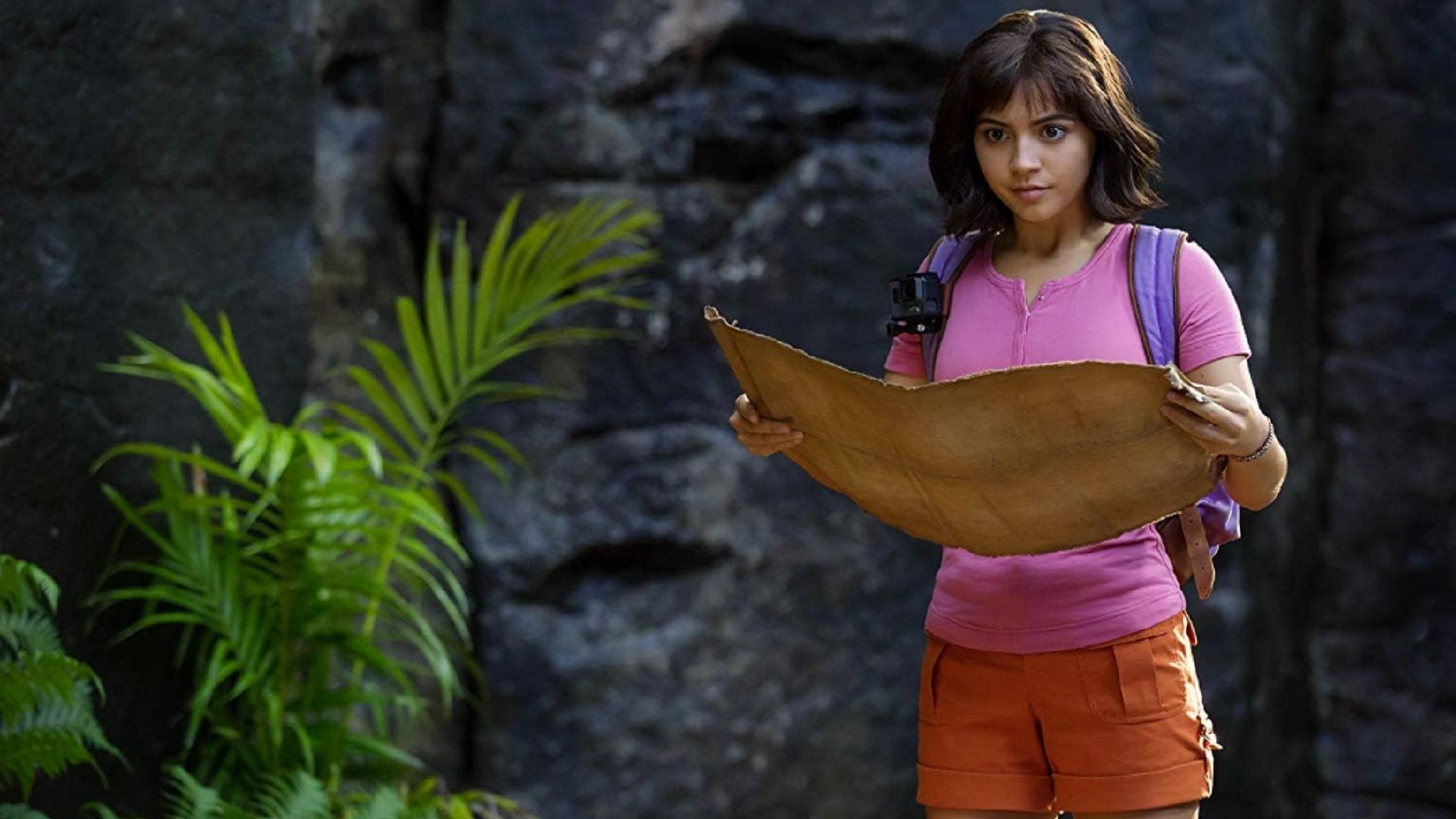 Dora la Exploradora mira hacia adelante, desplegando un mapa frente a ella