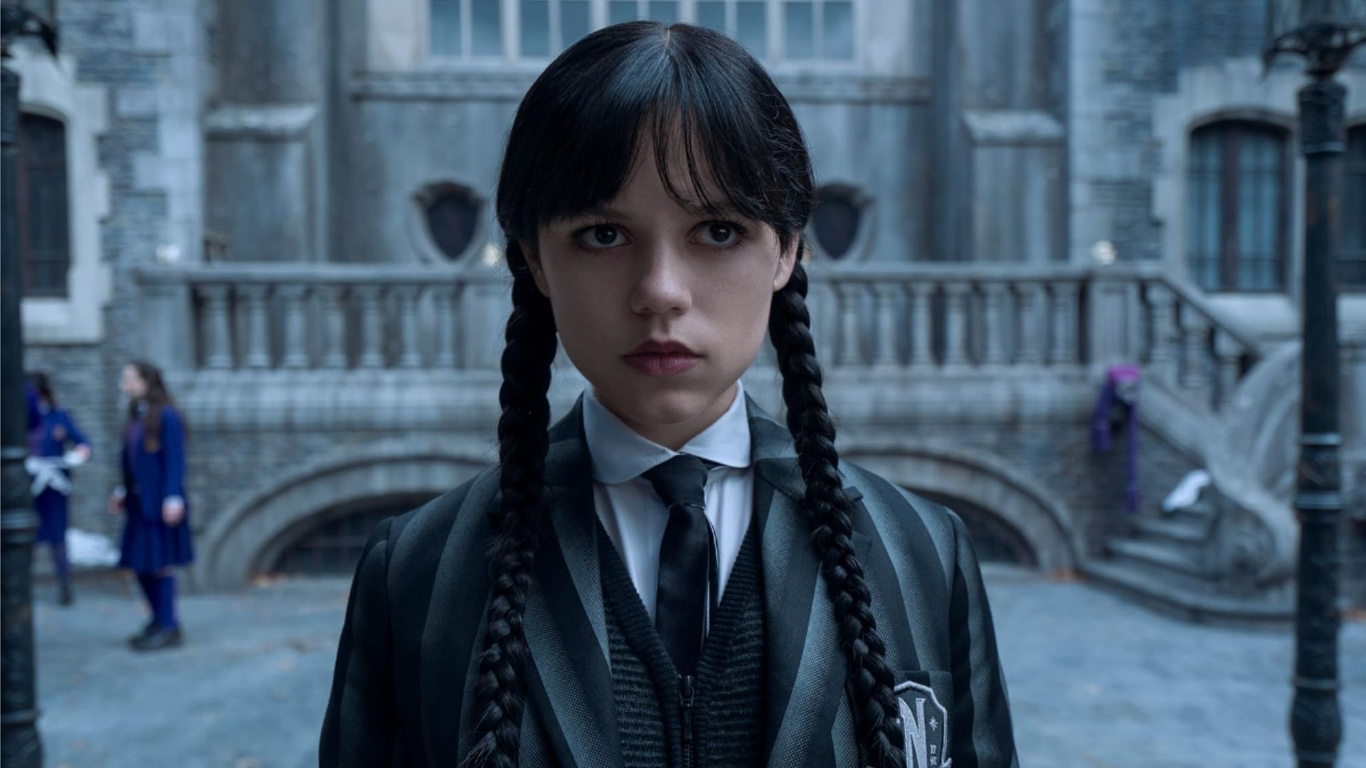 La actriz Jenna Ortega con atuendo escolar en una escena de la serie 'Wednesday', mirando hacia un lado sin emoción