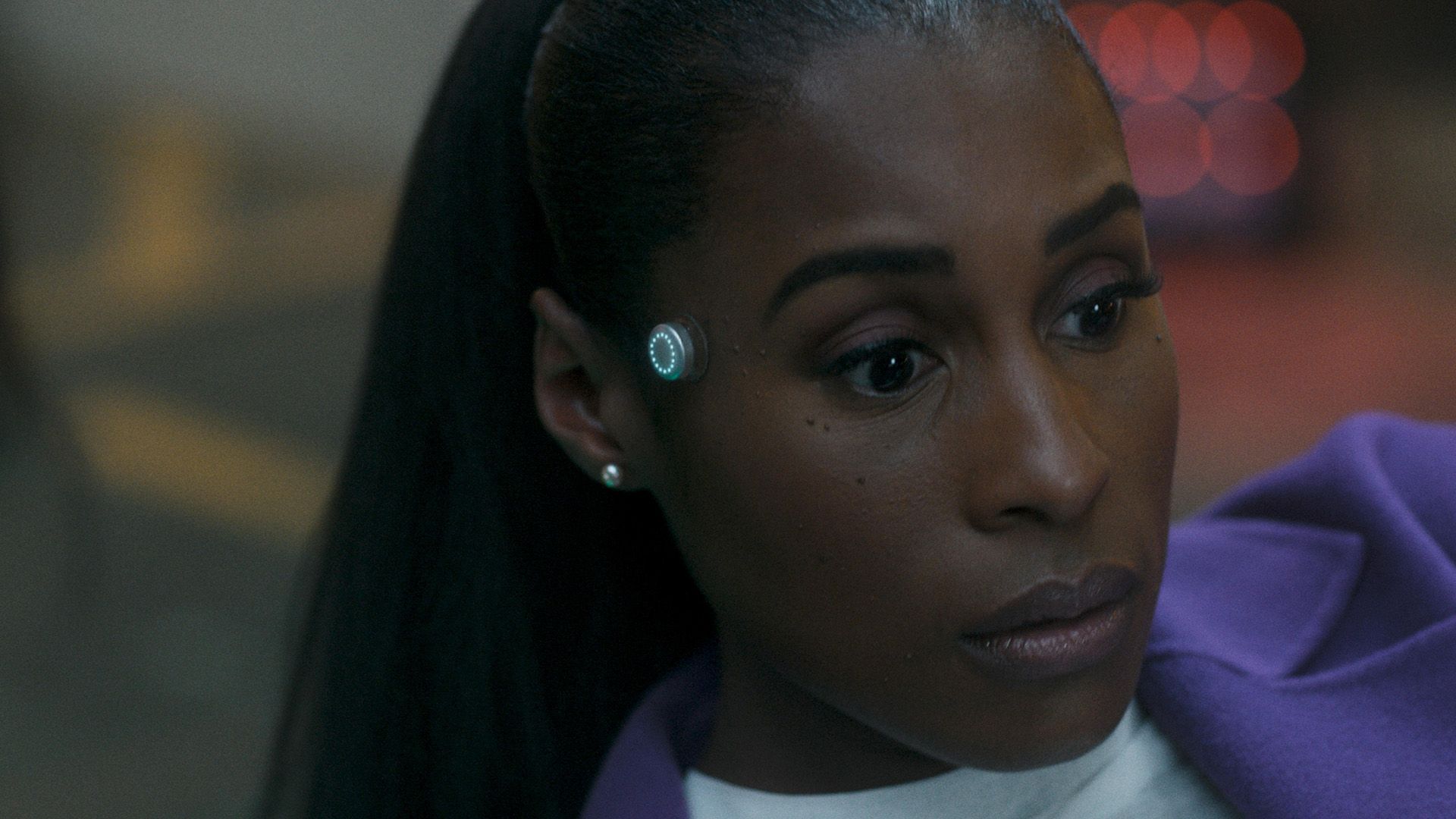 Issa Rae mira pensativamente hacia un lado, con un indicador metálico redondo brillando en su sien