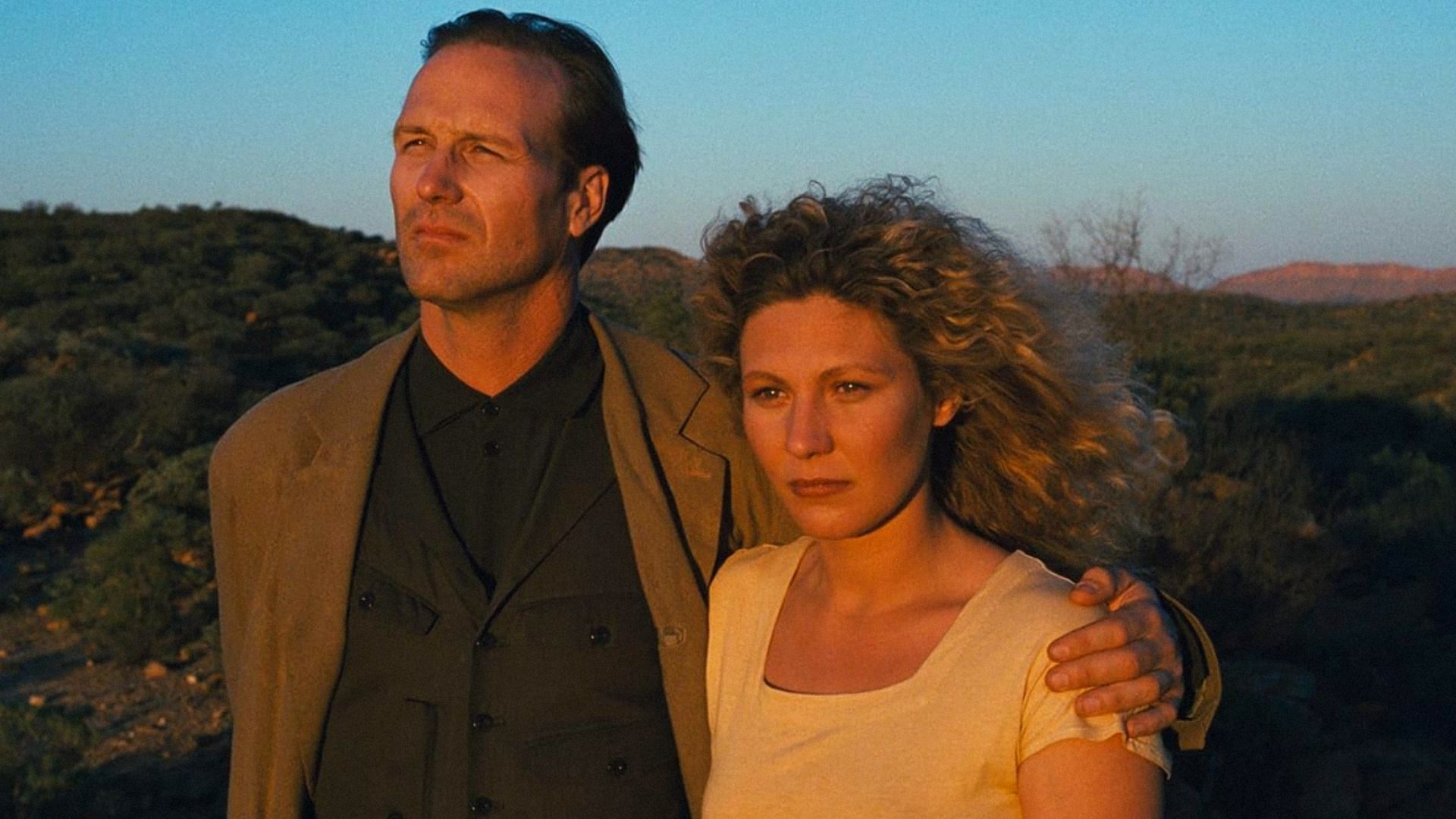 El actor William Hurt con chaqueta marrón abraza a la actriz Solveig Dommartin con camiseta blanca